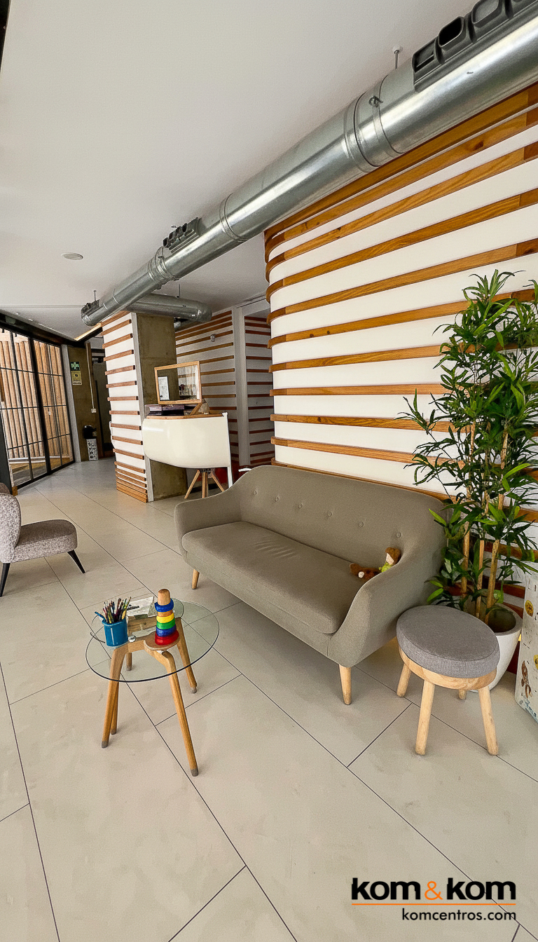 Recepción clínica dental de Alicante. con sofás y sillones. Decoración con listones de madera. paredes color blanco y suelo gris.